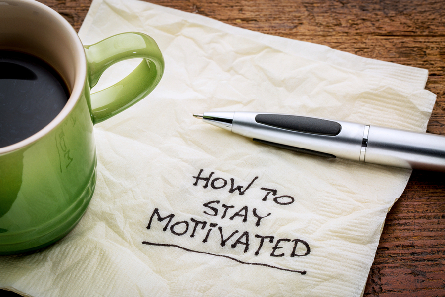 how to stay motivated note with a pen and coffee cup