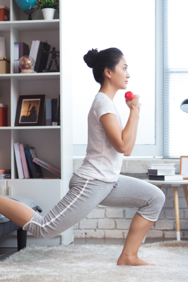 woman working out at home with a lunge and dumbbell